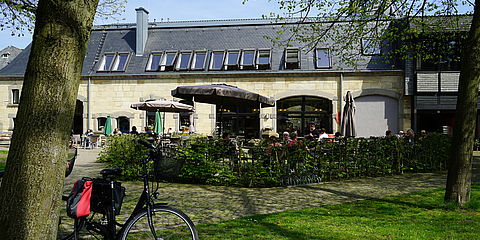 Blick auf die Außenterrasse des Cafés am Turm. Dahinter die Sandsteinfassade des Gebäudes.