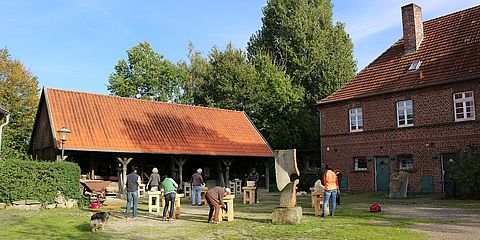 TeilnehmerInnen eines Bildhauerkurses bearbeiten im Innenhof des Sandsteinsmuseum ihre Werksteine.